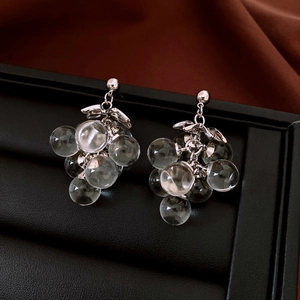 Close-up of crystal grape cluster earrings with silver needles on a black jewelry tray