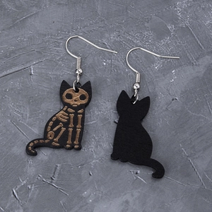 Detail of wooden black cat skeleton earrings with gold bone patterns for Halloween