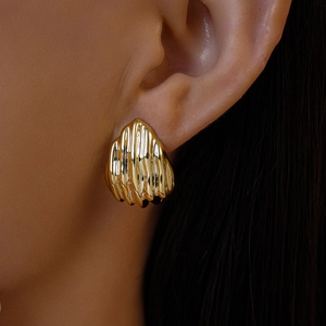 Gros plan sur les boucles d'oreilles dorées texturées portées par un mannequin élégant