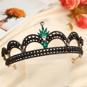 Close-up of Baroque vintage crown featuring black beads and emerald green gemstones