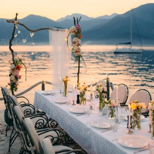 Romantic lakeside wedding dinner setup featuring white tablecloth with pink gold polka dots