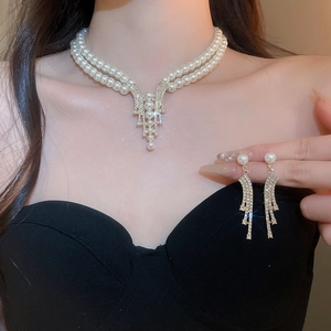 Close-up of elegant gold pearl necklace and earrings set worn by a model in black