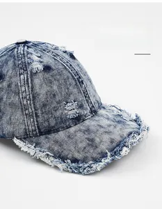 Detail of washed denim baseball cap featuring distressed ripped holes and frayed brim edges