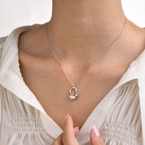 Detailed view of irregular hollow teardrop pendant on minimalist silver chain necklace