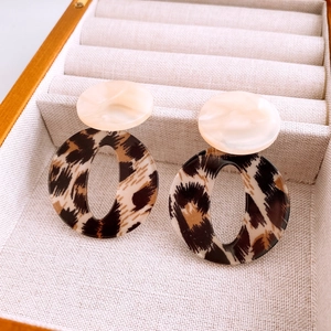 Close-up of leopard print acrylic drop earrings with beige studs in a velvet jewelry box