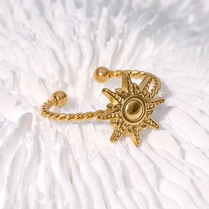 Golden sun open ring in stainless steel with twisted band on white textured background