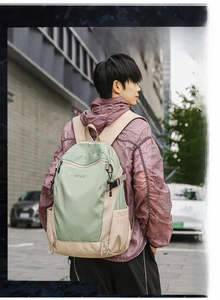 Outdoor backpack on model showing green and beige color blocks and side straps