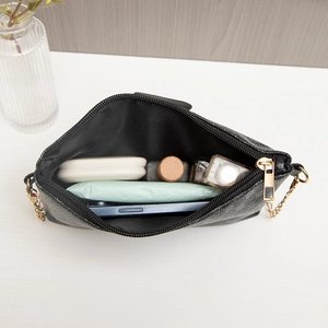 Textured black crossbody bag with gold chain strap showing internal storage capacity