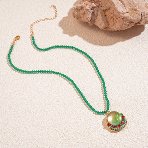 Detail of bohemian green beaded necklace with colorful round pendant on textured surface