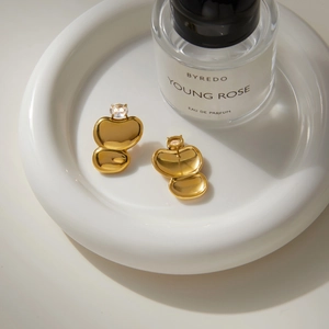 Detail of gold oval earrings with clear zircon, showing the elegant front and back views