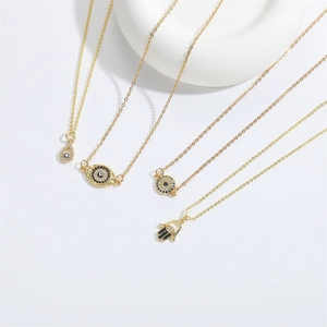 Golden Hamsa Hand and Evil Eye pendant necklaces displayed on minimalist white props