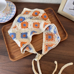 Detail of hand-crocheted floral headscarf in blue and orange on a wooden tray