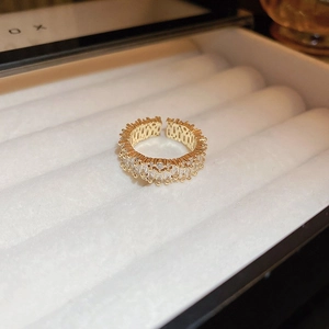 Top view of gold open ring with square and round zircons in a white velvet jewelry box