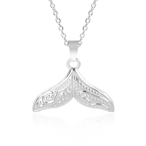 Macro view of a silver stainless steel whale tail pendant with intricate engraved patterns