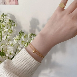 Detail of gold layered bead bracelet and a signet ring engraved with the letter J