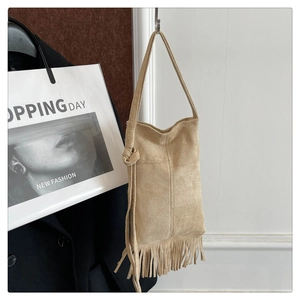 Detail of khaki suede tote bag featuring bohemian tassels and a knotted shoulder strap