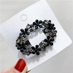Detailed view of a vintage hollow black crystal floral hair clip on white card display