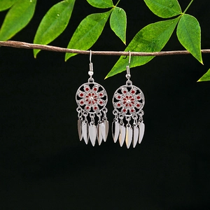 Detail of bohemian silver earrings with red floral pattern and feather tassel pendants