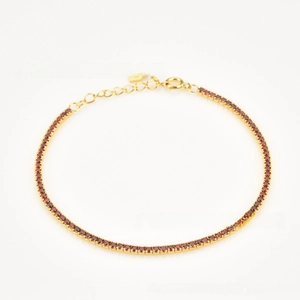 Close-up of golden tennis bracelet with deep red round-cut stones and adjustable clasp