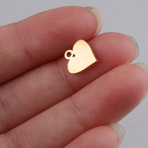 Close-up of a small golden heart pendant made of polished steel for DIY jewelry