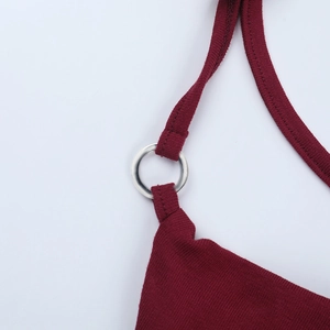 Détail macro du tissu en maille côtelée bordeaux et de l'anneau métallique sur la robe