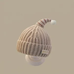 Close-up of camel knit baby hat with white pompom and soft textured ear flaps
