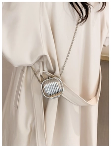 Detail of silver mini suitcase crossbody bag with metallic chain and grooved texture