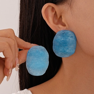 Detail of blue candy-colored acrylic oval earring with textured finish on model