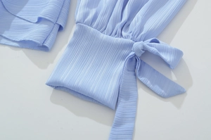 Détail d'une manche lanterne plissée bleu clair avec un nœud réglable sur le poignet