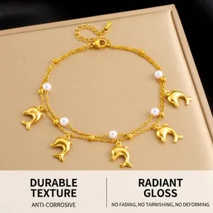 Detail of double-layer gold anklet featuring 3D dolphin charms and white pearl beads