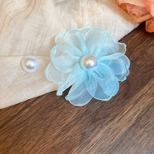 Detail shot of light blue mesh chiffon flower earrings with pearls on dark wood