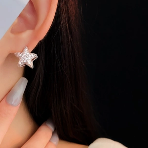 Detailed view of silver star earrings with pave cubic zirconia on female ear model
