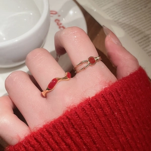 Detailed close-up of gold plated ring with red enamel finish worn on finger