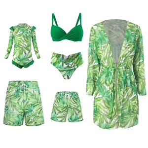 Flat lay detail of family tropical leaf swimwear set with green bikini and beach shorts