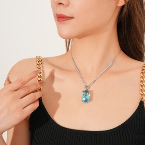 Close-up of a square sea blue gemstone necklace with silver diamond-set chain on a model