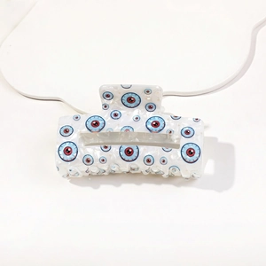 Detail of white acetate hair claw clip featuring blue and red eye print pattern