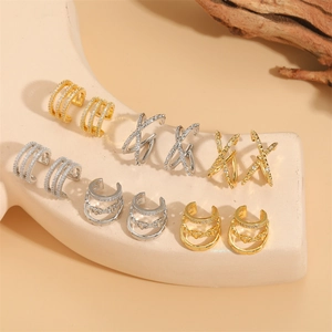 X-shape zircon ear cuffs and multi-layer gold earrings on minimalist beige display stand