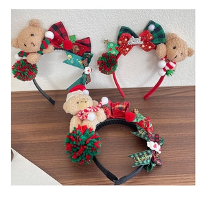 Detail of Christmas plush bear headbands with festive bows and pinecones on a wooden surface