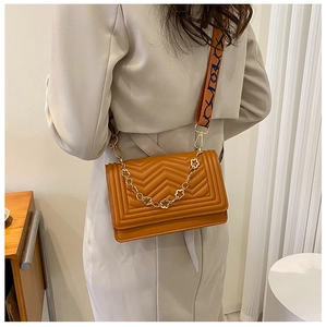 Detail of caramel quilted crossbody bag with chevron pattern and woven strap