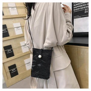 Détail du petit sac bandoulière noir plissé avec boucle en perle et texture gaufrée