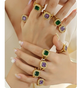 Macro view of gold-plated rings with emerald green and violet square zircon stones