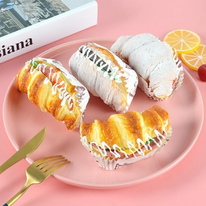 Detailed overhead view of four assorted artificial croissant sandwiches on a pink plate