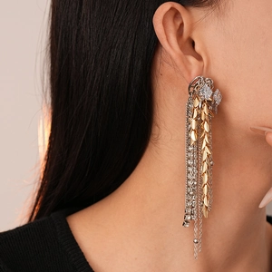 Macro detail of mixed-metal fringe earrings with wheat spikes and zircon crystals