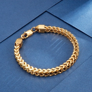 Detail of a golden braided keel chain bracelet with lobster clasp on a blue surface