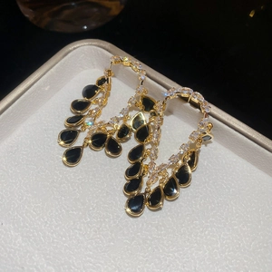 Detail of 18K gold plated earrings with white zircons and black pear-shaped drops