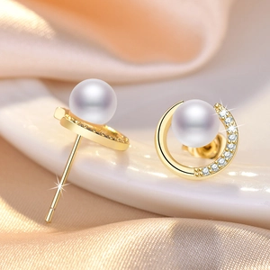 Elegant pearl and zircon stud earrings with C-shaped gold base on champagne silk