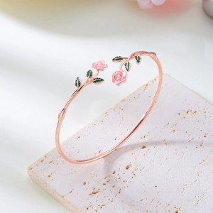Close-up of rose gold cuff bracelet featuring pink enamel rose and green leaf details