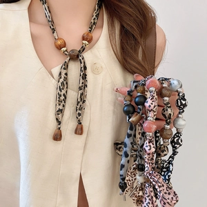 Détail du collier foulard imprimé léopard avec perles montrant divers coloris