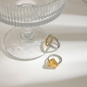 Vue détaillée de bagues cœur bicolores or et argent sur surface en verre