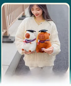 Cute capybara plush toy set in graduation cap and gown held by a model for gift ideas